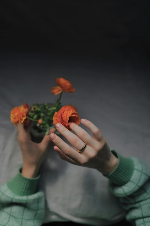 the hands are holding flowers in a glass bowl