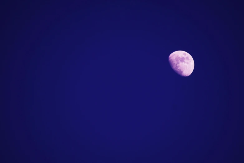 a half moon is shown lit against the dark blue sky