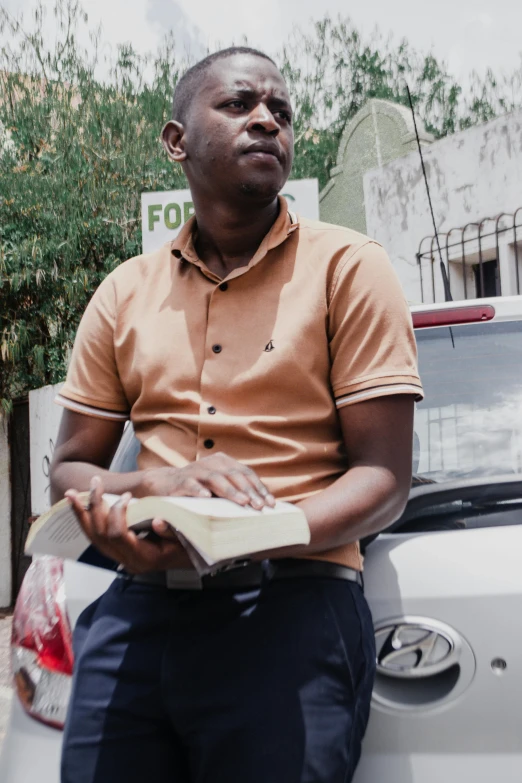 man sitting on the hood of a car with his hands folded