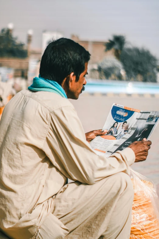 the man is sitting down and reading the newspaper