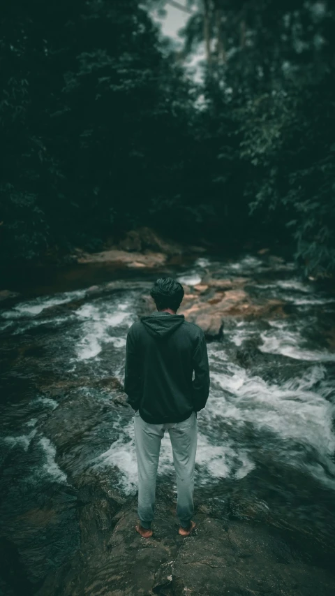 man standing on a riverbank watching the water