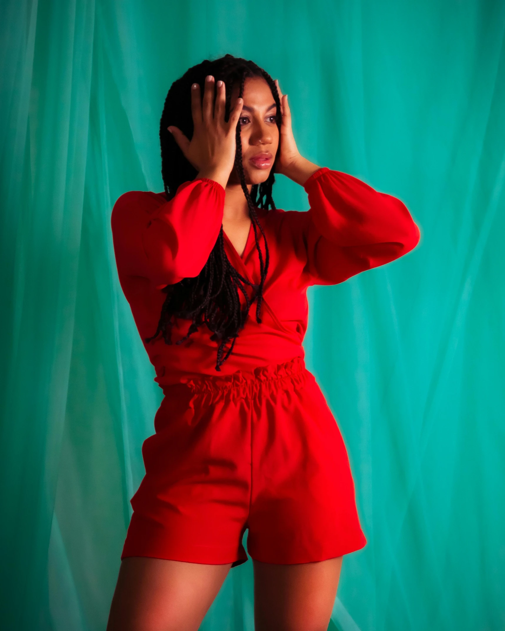 a woman in a red outfit with her hands on her head