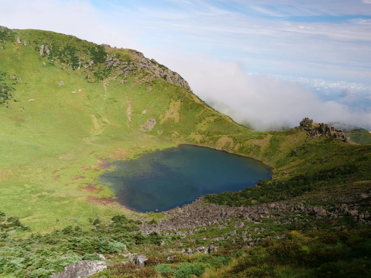 a mountain landscape with a lake surrounded by clouds