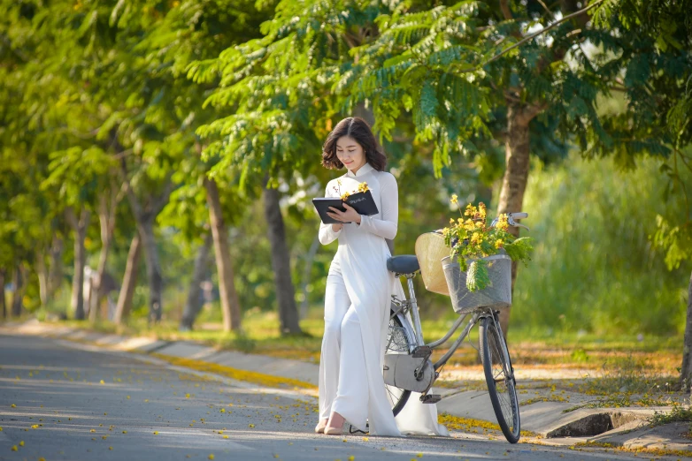 the girl is reading the book next to her bike