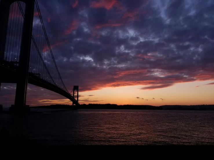 clouds over water at dusk with the bridge in background