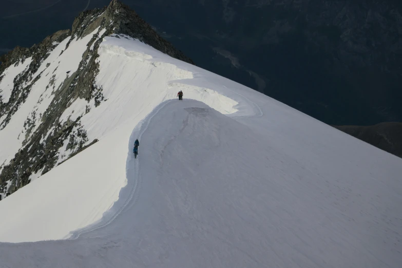 the two skiers are hiking up to the summit of the snow covered mountain