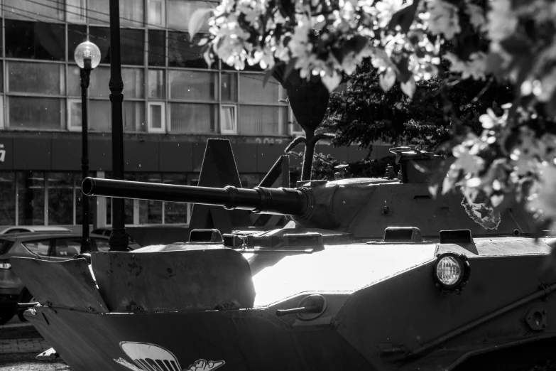 a tank parked by a tree in front of a building