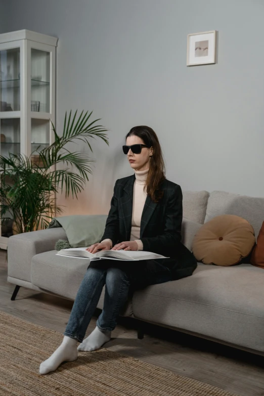 the woman sits on a couch reading a book