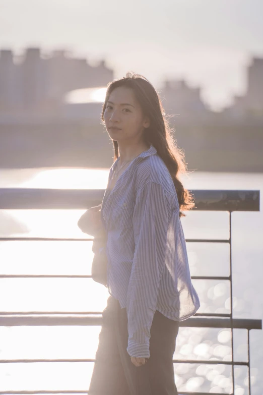 a woman stands near the railing with a laptop and headphones