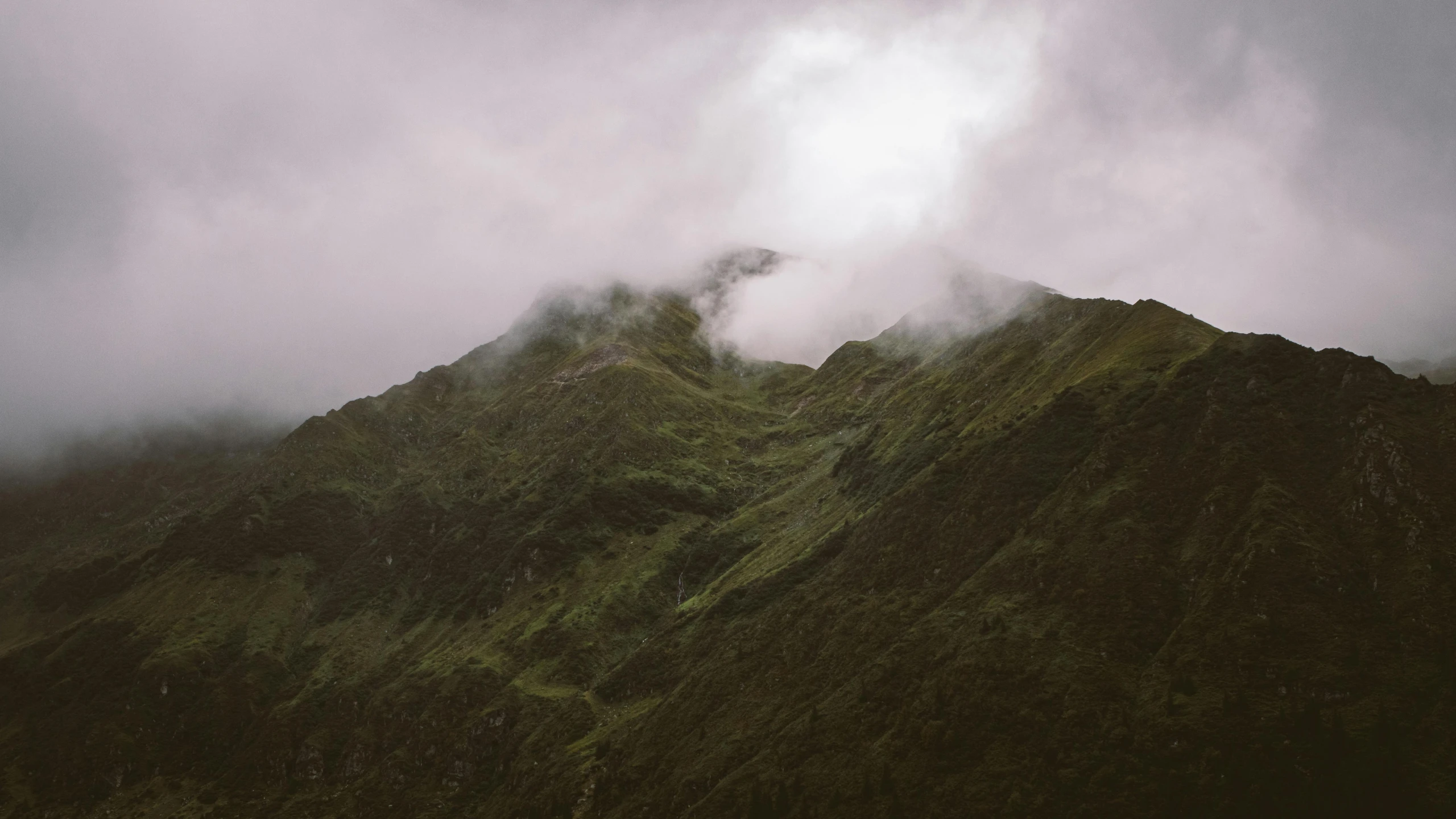 a large mountain is covered in thick fog