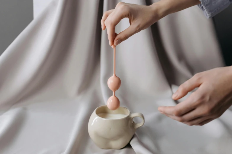 a person holding a wooden spoon pouring milk into a creamer