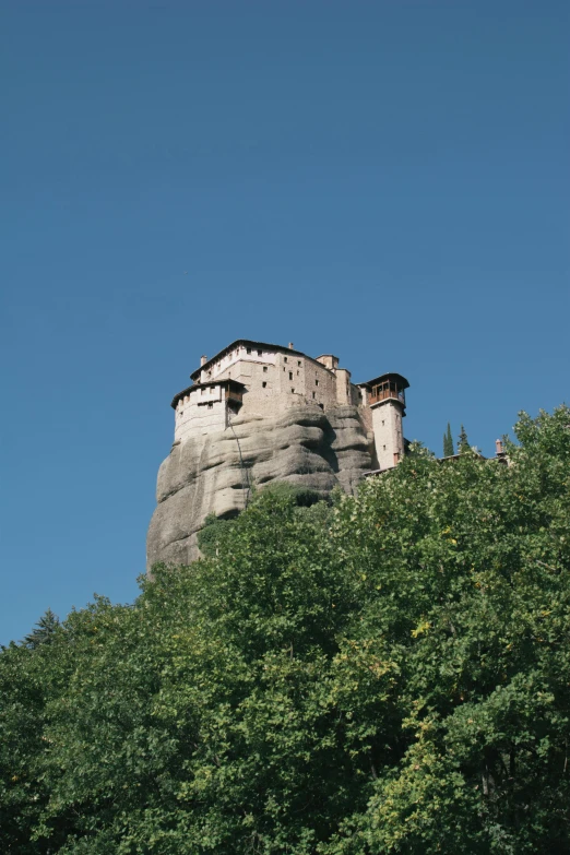 a rock tower with trees in the foreground and blue skies above