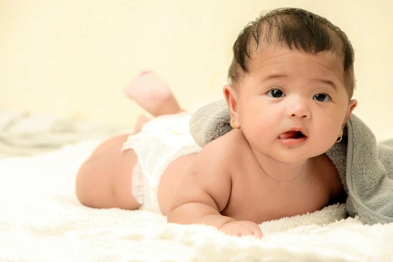 an adorable baby laying on top of white blankets