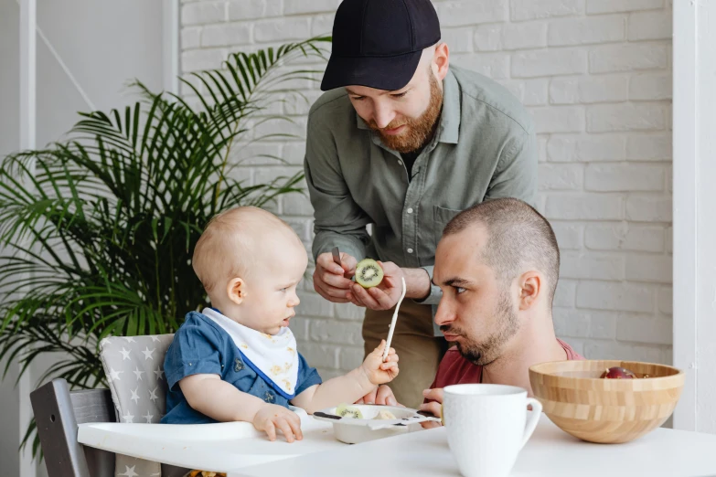 a man feeding his baby a piece of broccoli