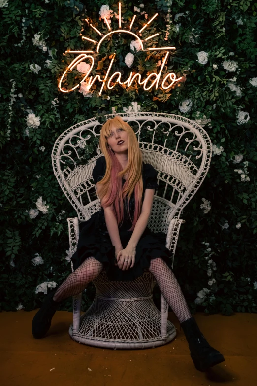 a beautiful blonde sitting on top of a chair next to a sign