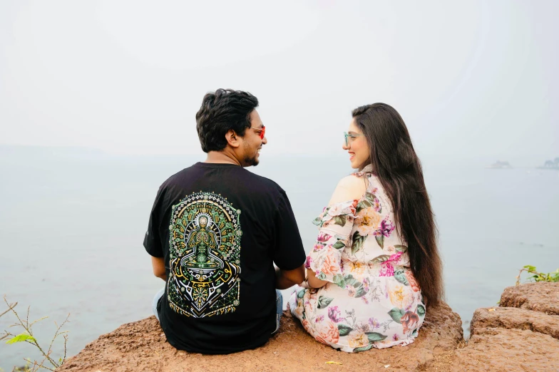 the couple is sitting on the edge of a cliff