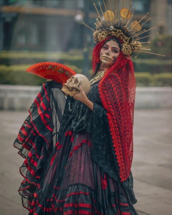a woman in an elaborate costume holding a bird and a human skull