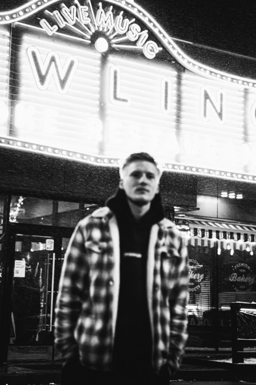 man standing in front of a theater with the marquee lit up