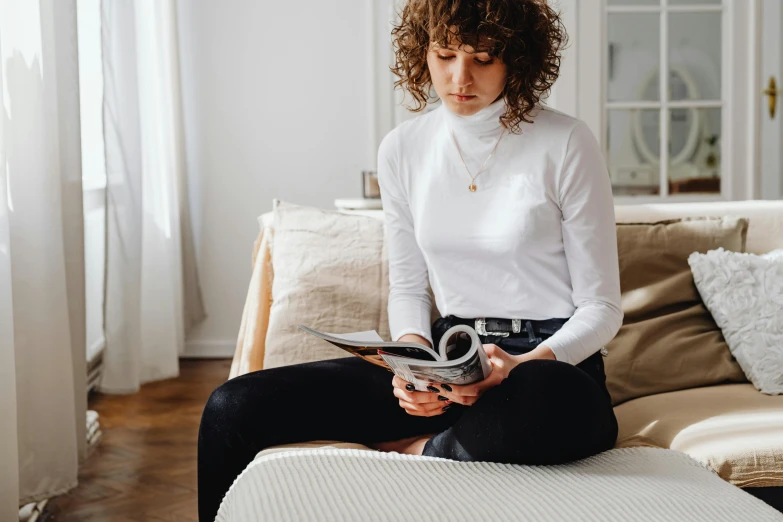 the woman is sitting on her couch and holding a pair of scissors