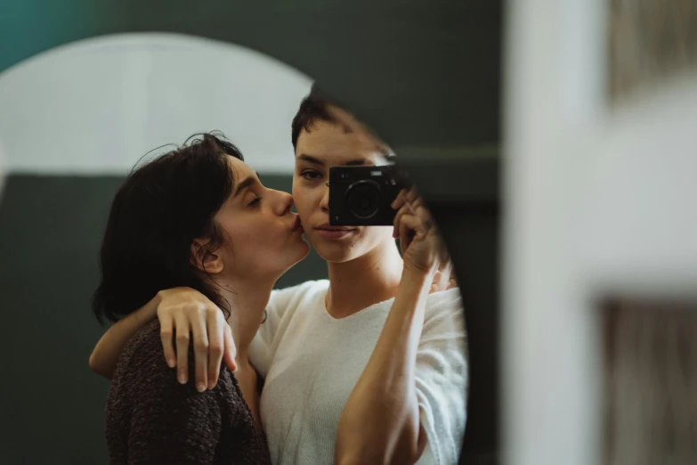 two people taking pictures in front of a mirror