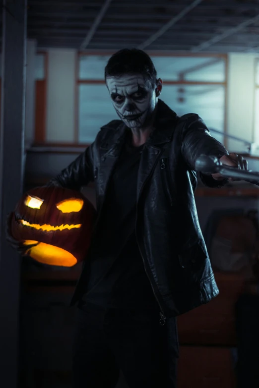 a man in black leather jacket holding a pumpkin