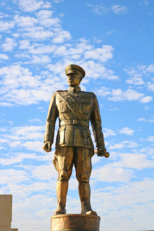 a statue of a soldier wearing a hat standing in front of clouds