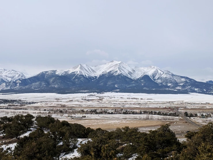 a large snow covered mountain sitting above snow covered forest