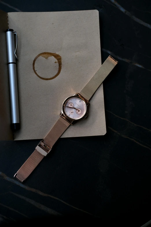 a watch sits on a napkin next to a pen