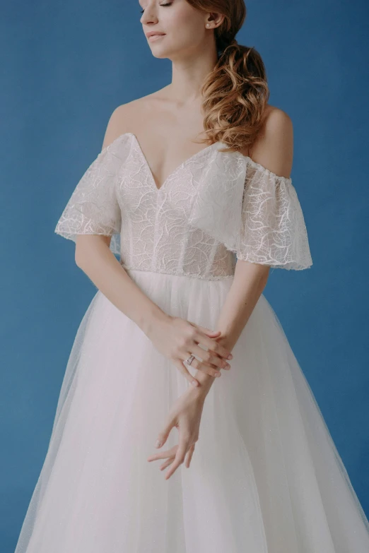 a woman in white wedding dress with her hand under her belly