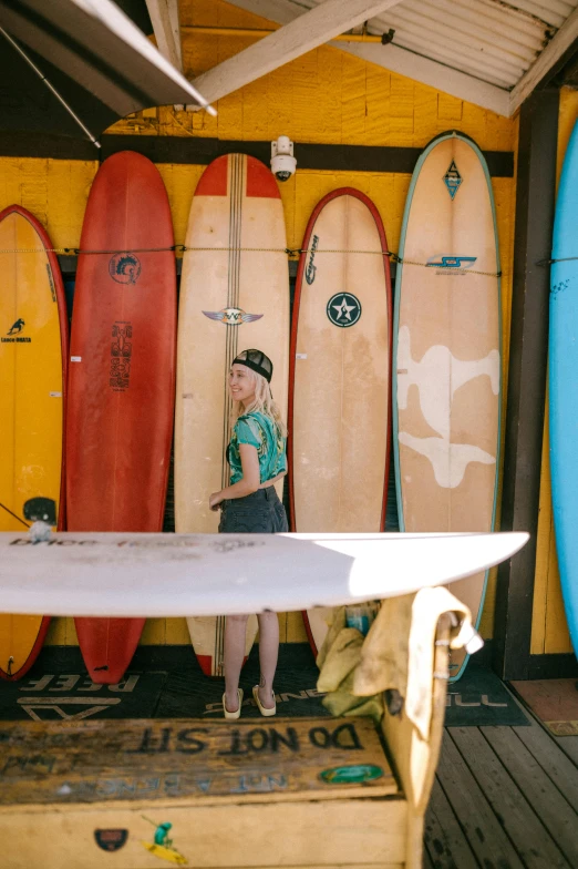 a woman standing next to a bunch of surfboards