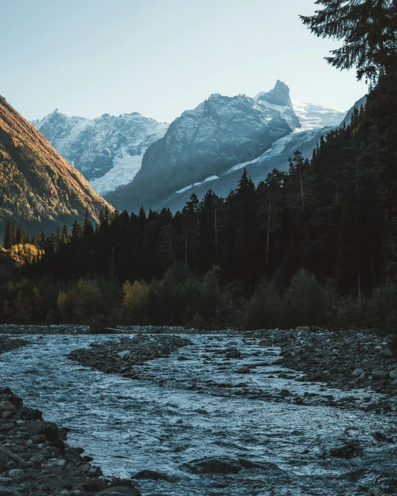 a mountain scene with a river in the foreground