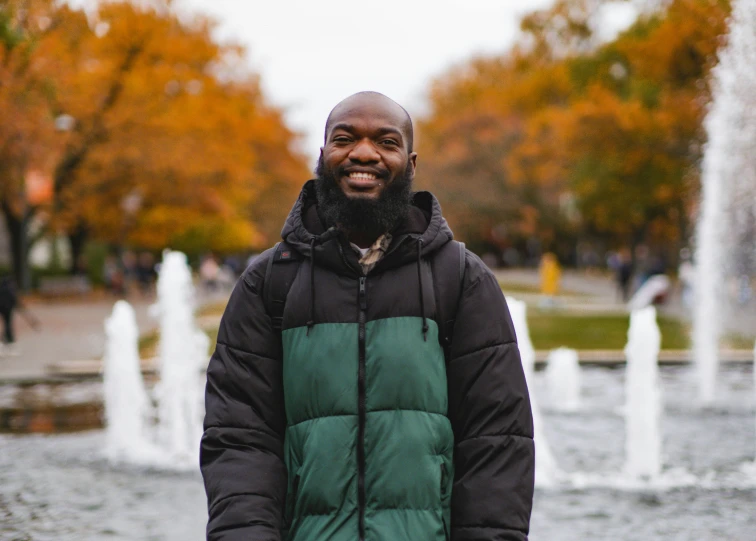 a man with a beard in front of a fountain