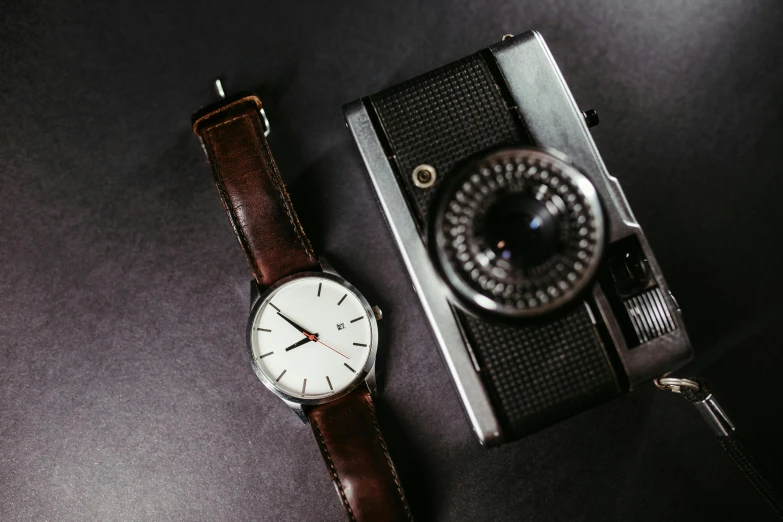 a watch and camera lying next to each other