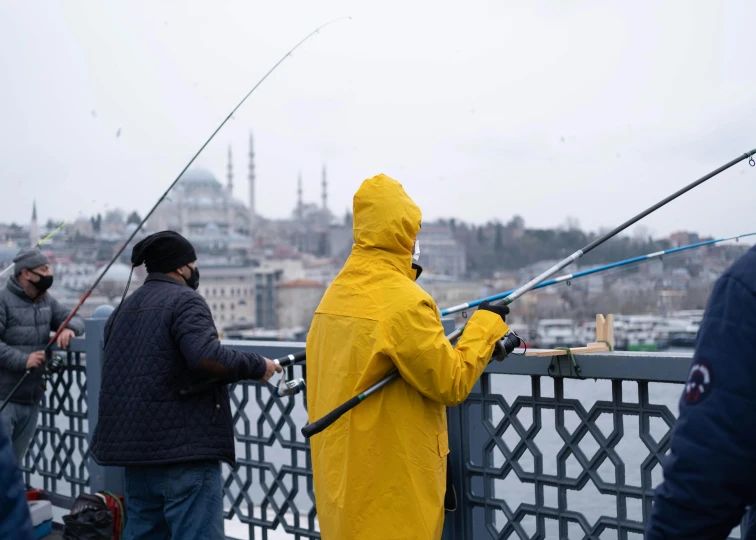 people in yellow jackets are fishing on a bridge