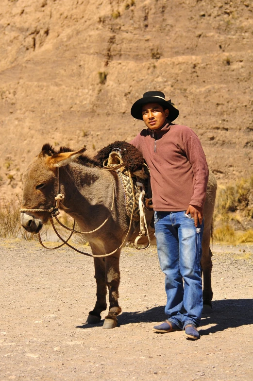 the little boy is standing next to a donkey