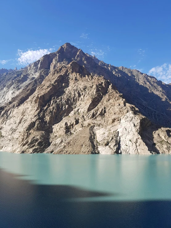 a blue lake next to a mountain under a blue sky