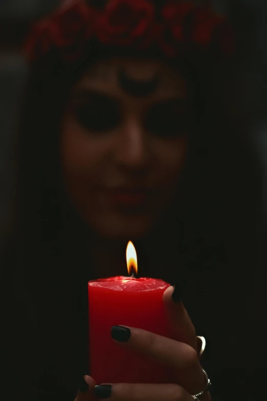 a person holding a red candle in their hand