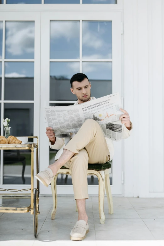 man sits on golden chair and reads the paper