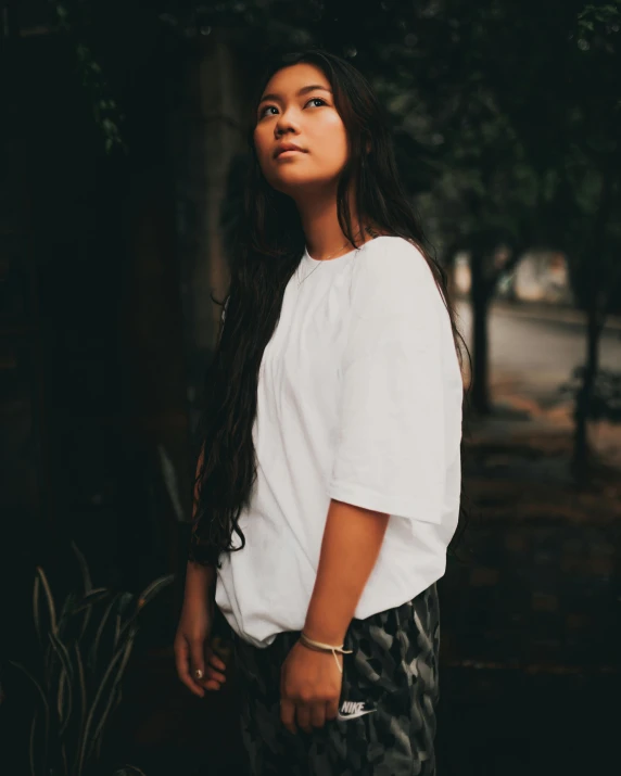 a woman with long hair standing next to a tree