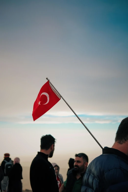 people at the beach standing in line with a flag