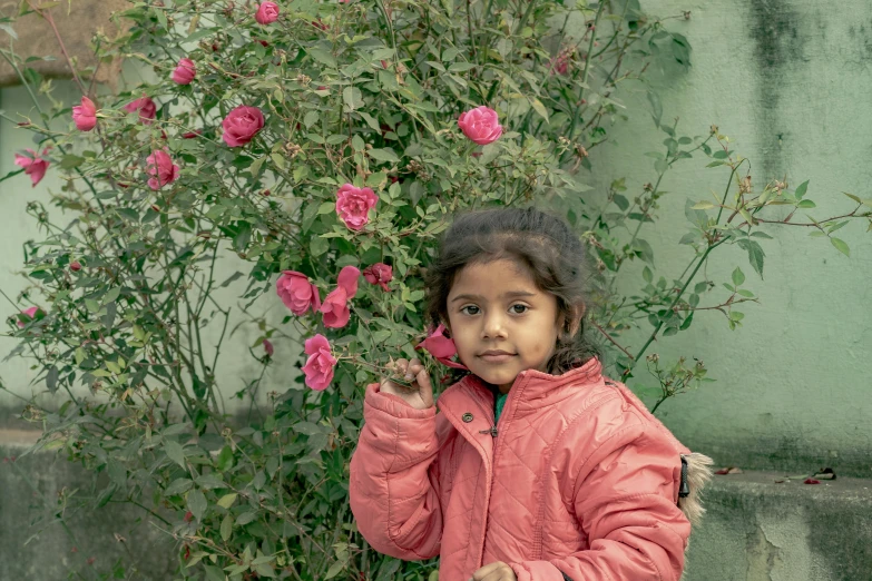 a girl standing in front of some pink flowers