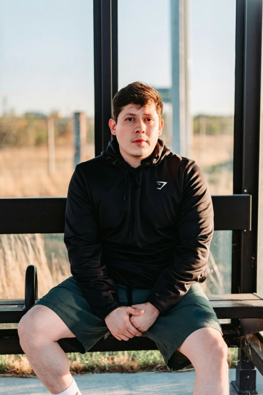 man sitting on park bench in front of bus terminal