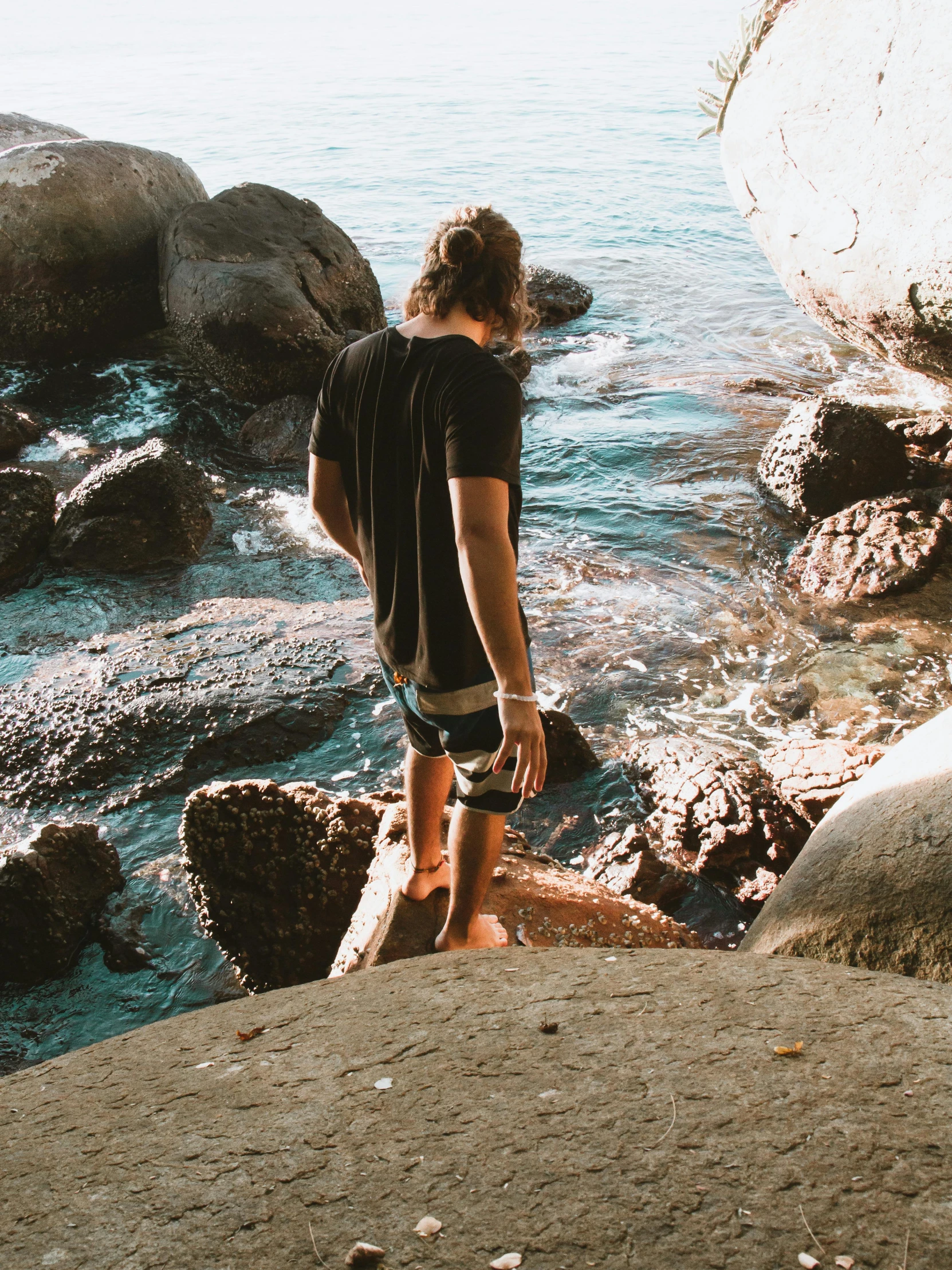 a man looking out at the ocean with his skateboard