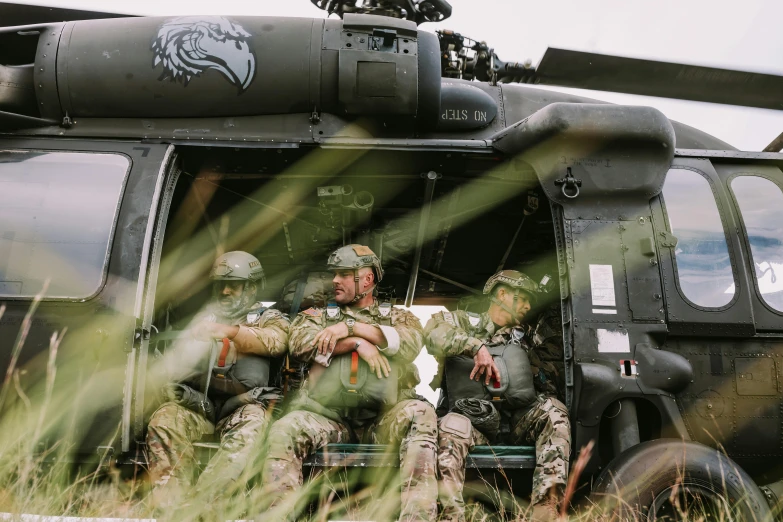 a couple of men sitting next to a large helicopter