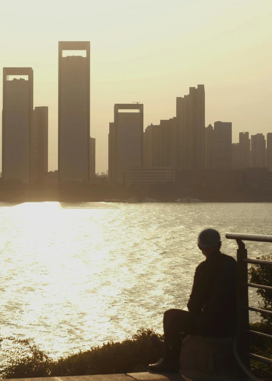 a man sitting on the edge of a stone platform looking out to water