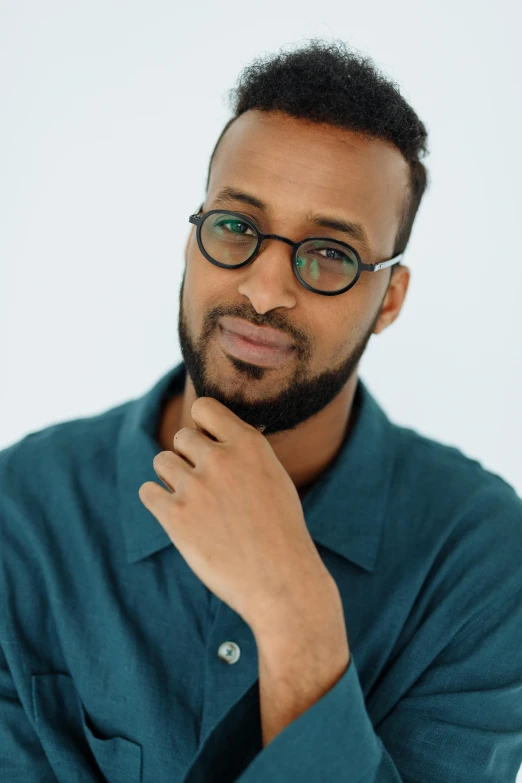 a man in a blue shirt and black glasses posing for a po