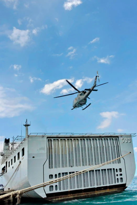 a large ship is near a helicopter flying overhead