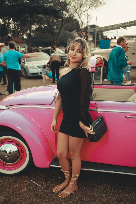 a lady posing in front of a pink car