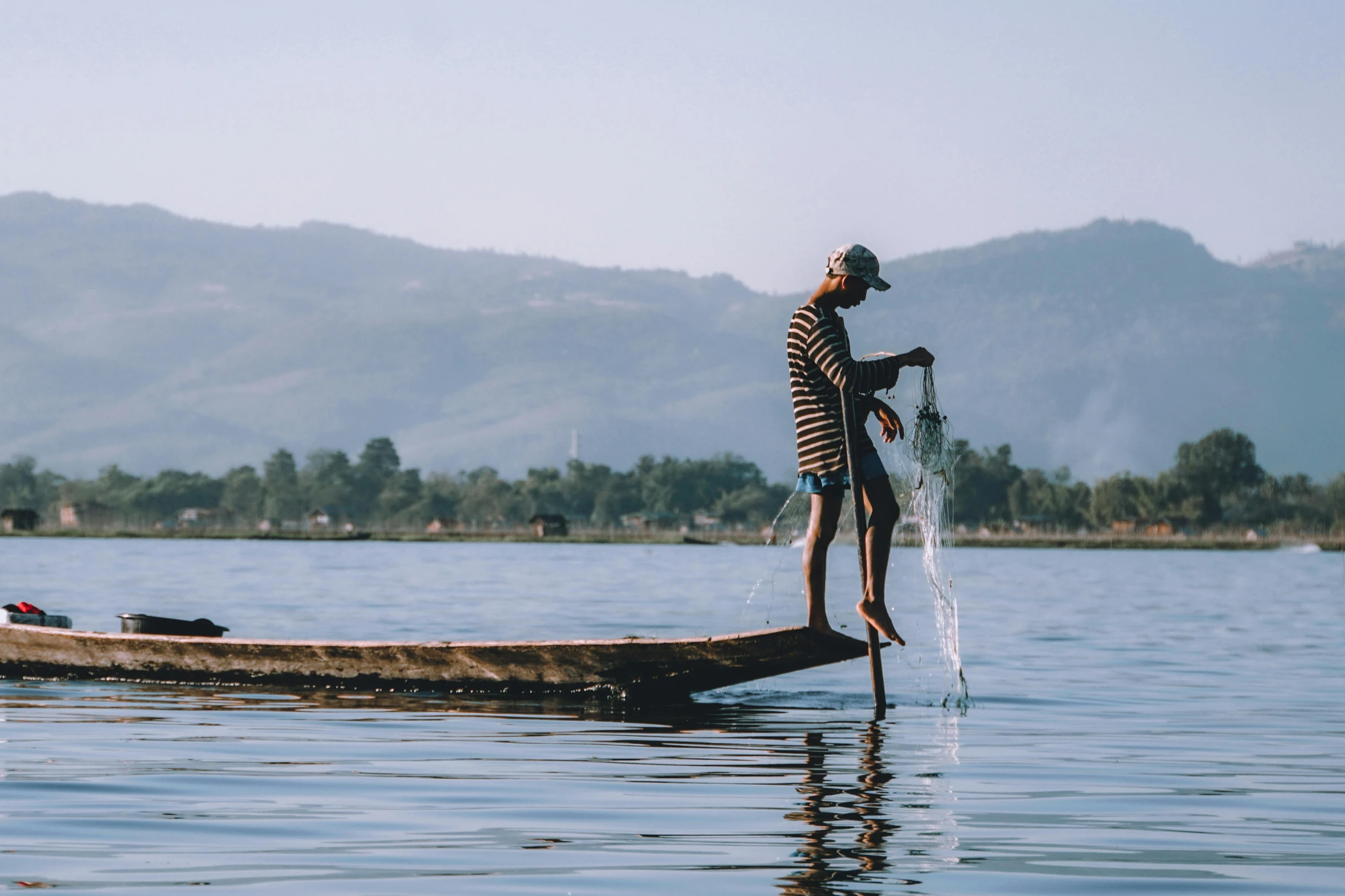 a boy standing on the side of a boat holding a net