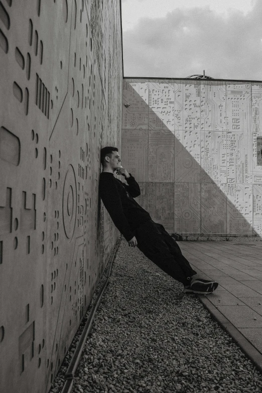 a man leaning against the side of a building with a phone